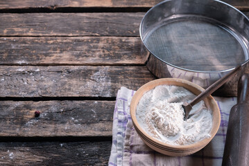 Old rural kitchen table with flour, cooking oil, sieve, towel and rolling pin background.