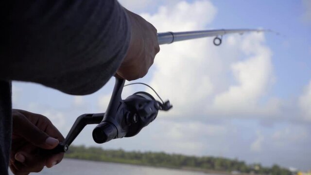 slow mo fishing reel and rod closeup blue sky cloudes beac
