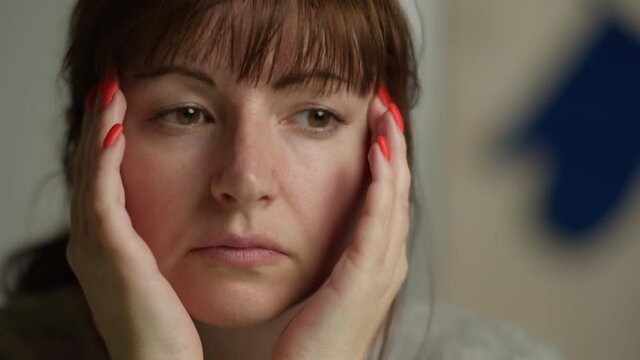 close-up of sad woman with headache doing massage herself
