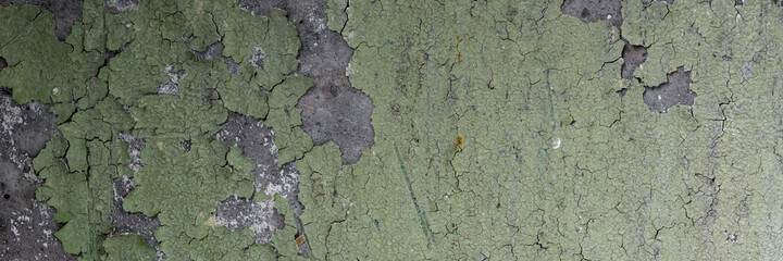 Peeling paint on the wall. Panorama of a concrete wall with old cracked flaking paint. Weathered rough painted surface with patterns of cracks and peeling. Wide panoramic texture for grunge background