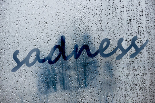 Word Sadness Written On Foggy Window With Rain Drops