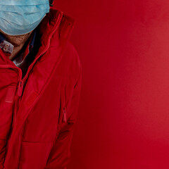 man in red jacket is using a protective mask against corona virus on red background, red color symbol of high alert and stop sign against the disease