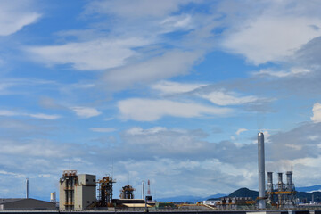 夕陽をバックに白い煙を出す4本の煙突