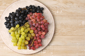 clusters of green red and black grapes on a plate