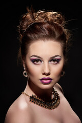 Young beautiful lady with bright make-up and luxury accessories on dark background