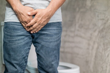 Men bladder problem concept : Man standing in the toilet and want to peeing and feeling pain in his penis - obrazy, fototapety, plakaty