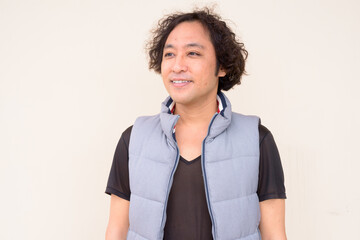 Portrait of happy Japanese man with curly hair thinking