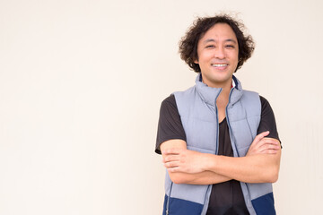 Happy Japanese man with curly hair smiling with arms crossed © Ranta Images