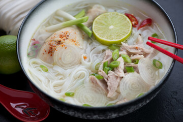 Close-up of Pho Ga Hanoi or vietnamese chicken noodle soup served in a black bowl, selective focus