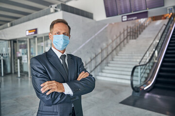 Mature businessman in mask flying on trip