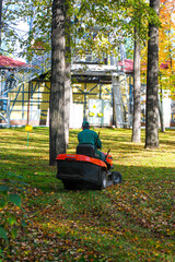 Perm, Russia/ 29/25/2020 Gorky Park. A special red machine removes fallen yellow and dry leaves from lawns and grass. Cleaning leaves in the Park.