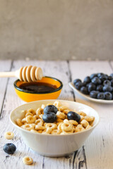 Honey rings with blueberries in a bowl on the table wooden background. Copy space. Flat lay. Horizontal orientation.