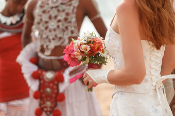 Bride hold in hand flower bouquet during traditional weddding in Sri Lanka, stand in front of dancers in costumes