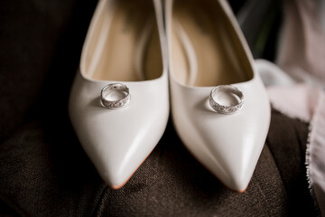 bride's shoes with wedding rings together