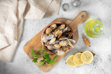 Boiled clams in a wooden bowl on a light gray table. Shellfish close-up. Seafood dish. Top view with space for text	