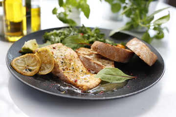 Salmon in lemon sauce. Appetizing dinner dish served with salad and bread.
Food photography, food styling.
