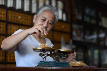 The old doctor of traditional medicine weight scales dry lotus pollen china herbs in chinese medicine shop.