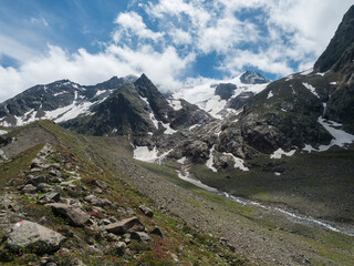 Summer view of alpine landscape with snow-capped mountain peaks and winding Freigerbach stream. Tyrol, Stubai Alps, Austria