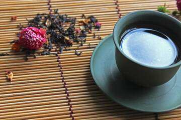 Traditional tea ceremony arrangement. Iron teapot, cups, dried rose buds over wooden table background