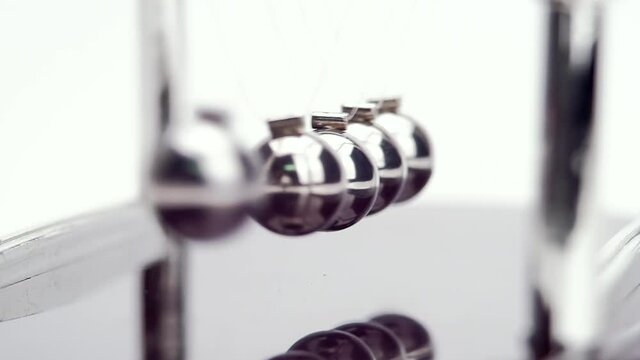 Slow motion shot of Newton's metal balls on white background. Close up.