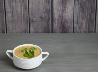 Pumpkin cream soup in a white Cup on a gray wooden background . Place for a copy space