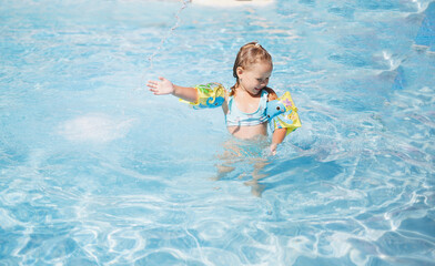 little girl swims in the pool in the outdoor water park