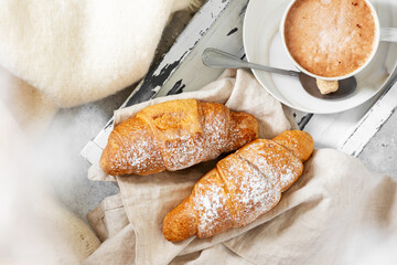 Croissants. Croissants and cappuccino on a wooden tray on a light background. French breakfast. Top view with copyspace