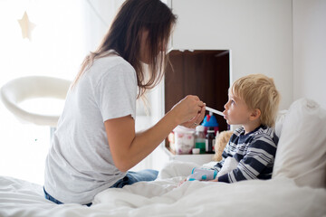Mother, checking her son for fever with digital thermometer