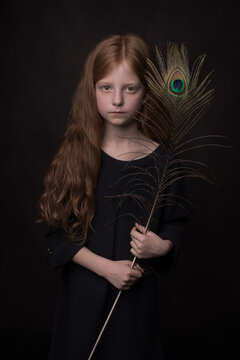 Portrait of girl holding peacock feather while standing indoors