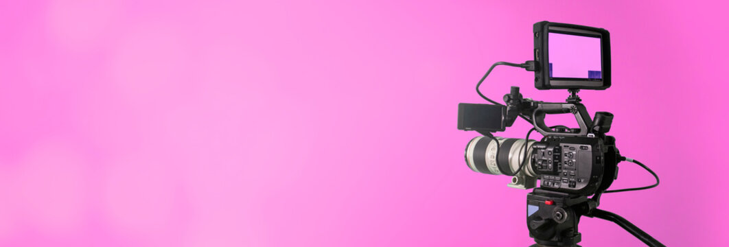 video camera on lighty pink background with bokeh, movie or television broadcasting banner	

