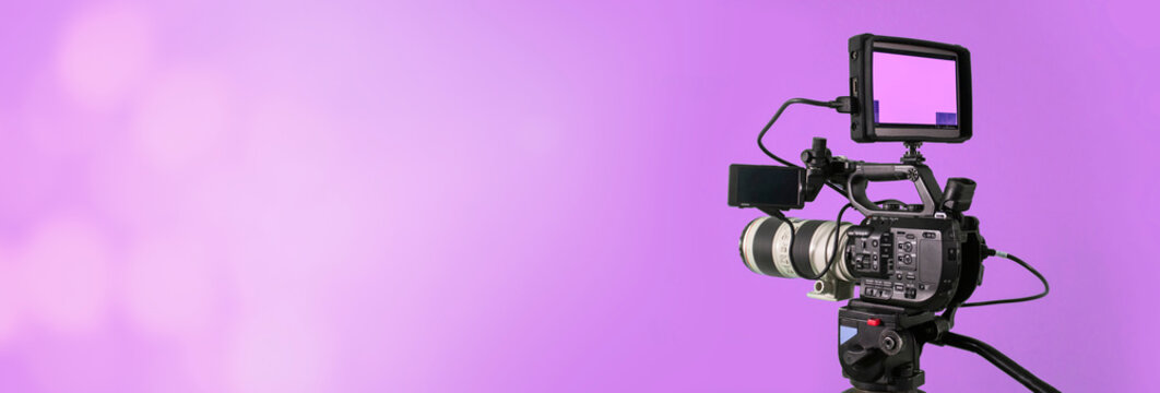 video camera on purple background with bokeh, movie or television broadcasting banner	
