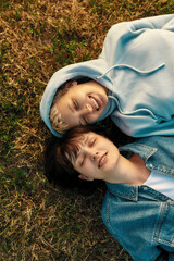 Top view of happy lesbian couple lying on the grass in summer park. Women in love smiling with closed eyes while spending time together outdoors