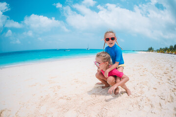 Little happy funny girls have a lot of fun at tropical beach playing together