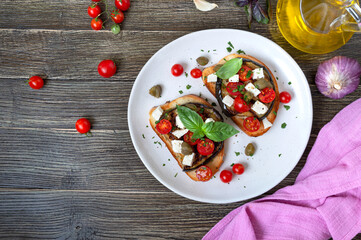 Garlic bruschetta with eggplant, feta, cherry tomatoes, capers. Useful vegetarian appetizer. Italian Cuisine.