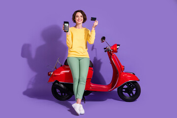 Fototapeta na wymiar Full length body size view attractive cheerful cheery glad girl sitting on bike using bank card terminal order shop isolated over bright vivid shine vibrant lilac violet purple color background