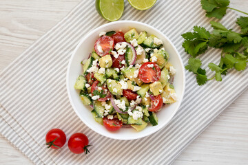 Delicious Avocado Tomato and Cucumber Salad in a bowl on cloth, top view. Flat lay, overhead, from above.