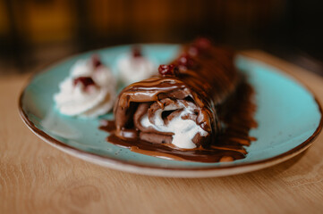 chocolate pancake with bananas, nuts and chocolate sauce. the toning. selective focus. a rolled chocolate pancake is a calorie bomb