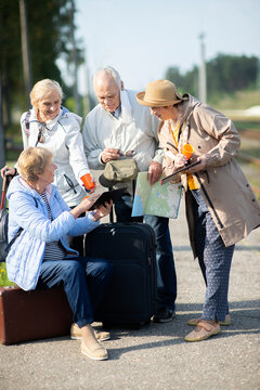 Group of positive senior people looking at map on traveling journey during pandemic.COVID-19 travel in the New Normal