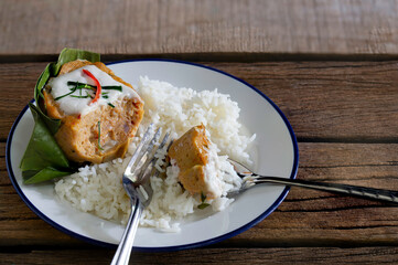 Cooked rice and Steamed fish with curry paste in banana leaf  on old wooden table which has black background