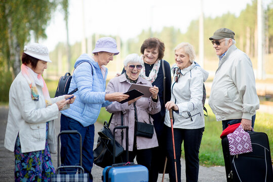 Group of positive senior elderly people looking at digital map on traveling journey during pandemic.COVID-19 travel in the New Normal.