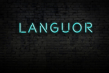 Neon sign. Word languor against brick wall. Night view