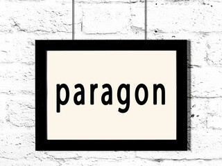 Black frame hanging on white brick wall with inscription paragon