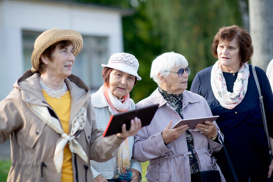 Group of positive senior elderly women looking at digital map on traveling journey during pandemic