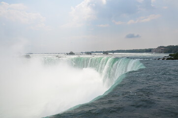 Closeup over the edge of the Canadian Niagara Falls in slightly cloudy weather