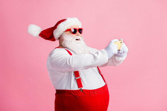 Profile side view portrait of nice bearded fat overweight guy Santa using gadget browsing post multimedia social network blog 5g app playing game air blow wind isolated pink pastel color background