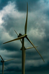 Wind turbines generating green electricity in a storm with dark clouds.