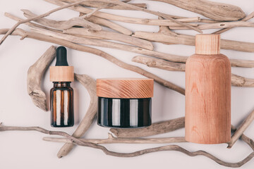 Top view of wooden and glass bottles containers blank mockup for skincare beauty cosmetic products for body or face on beige pastel background with driftwood. Beauty spa concept. Skin care routine.