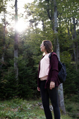 Woman hiker at mountain forest shined by the sun at sunset