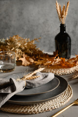 Autumn table setting with dry yellow oak leaves, fall decoration on grey table. Thanksgiving day