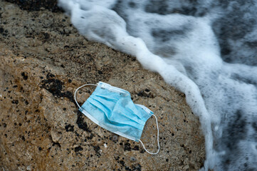 Waste during COVID-19. Scrapped to ocean coronavirus single-use face masks. Environmental and coastal plastic pollution. Trash on the beach that threatens the health of the oceans.